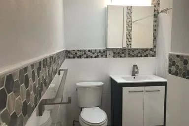 Bathroom after the remodel, with a navy vanity and hexagon tile band